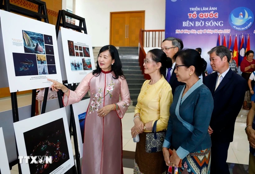 Bà Trần Thị Thu Đông, Phó Chủ tịch Liên hiệp các hội Văn hóa Nghệ thuật Việt Nam, Chủ tịch Hội Nghệ sĩ Nhiếp ảnh Việt Nam giới thiệu các bức ảnh với khách tham quan Triển lãm. (Ảnh: Phạm Kiên/TTXVN)